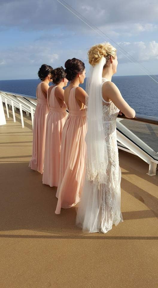 Bride and three bridesmaids with updos on a cruise ship deck at sunset