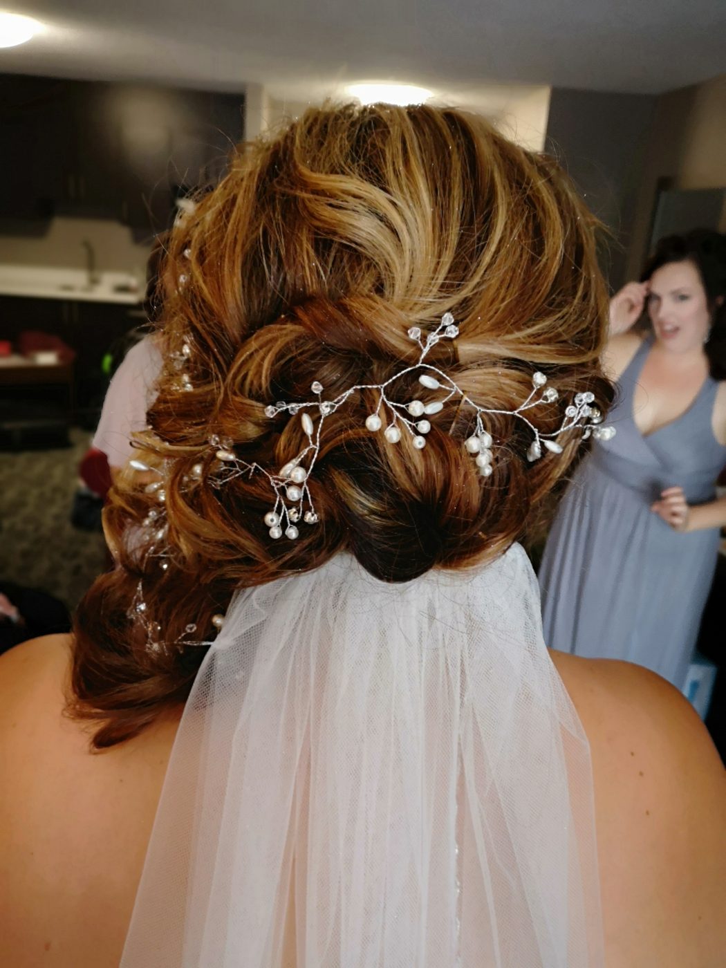 Bridal updo with a pearl and crystal hair vine, finished with a veil